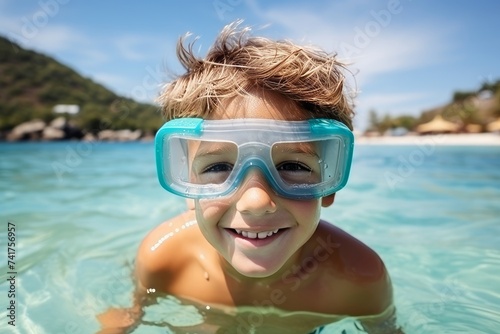 Portrait of cute little boy in swimming goggles and cap at tropical beach