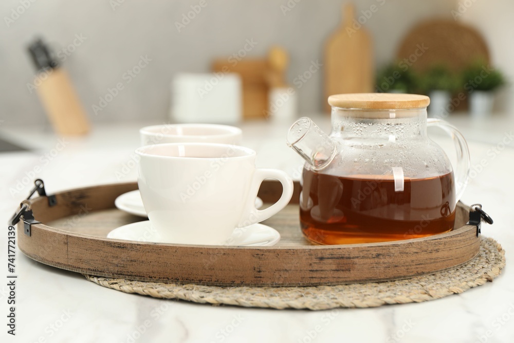 Aromatic tea in glass teapot and cups on white table Aromatic tea in glass teapot and cups on white table