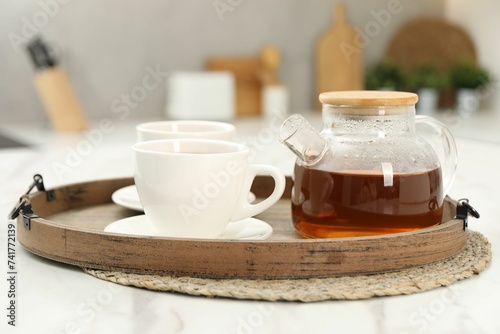 Aromatic tea in glass teapot and cups on white table