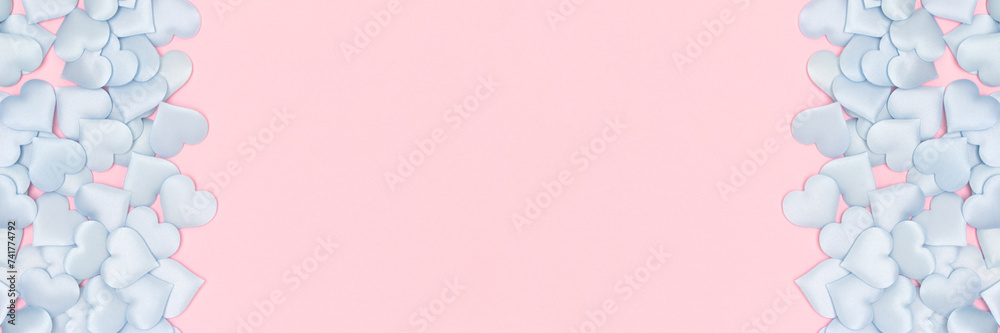 Banner with frame made of blue textile hearts confetti on a pink background. Festive composition with copy space. Banner with frame made of blue textile hearts confetti on a pink background. Festive composition with copy space.