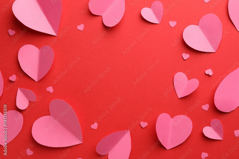 Frame of pink paper hearts on red background, flat lay. Space for text