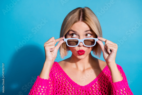 Photo portrait of pretty young girl touch 3d glasses look empty space wear trendy pink knitted outfit isolated on blue color background