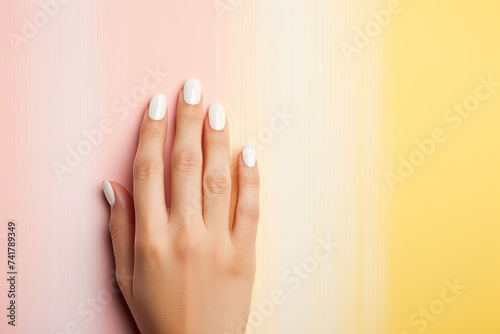 Beautiful woman hand with a white manicure on a bright yellow-pink background