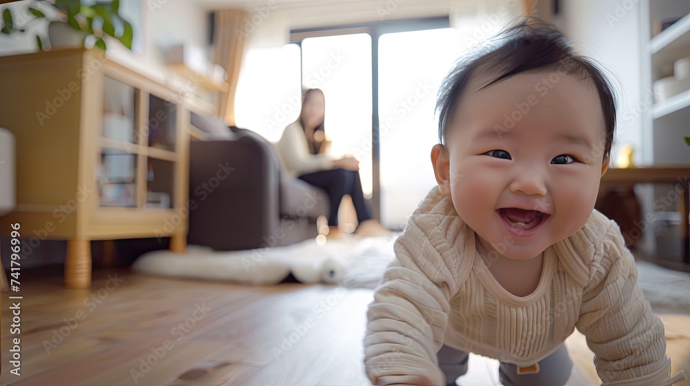 Asian baby smiles beamingly while crawling on the floor while a mother watches from behind while sitting on the sofa Asian baby smiles beamingly while crawling on the floor while a mother watches from behind while sitting on the sofa