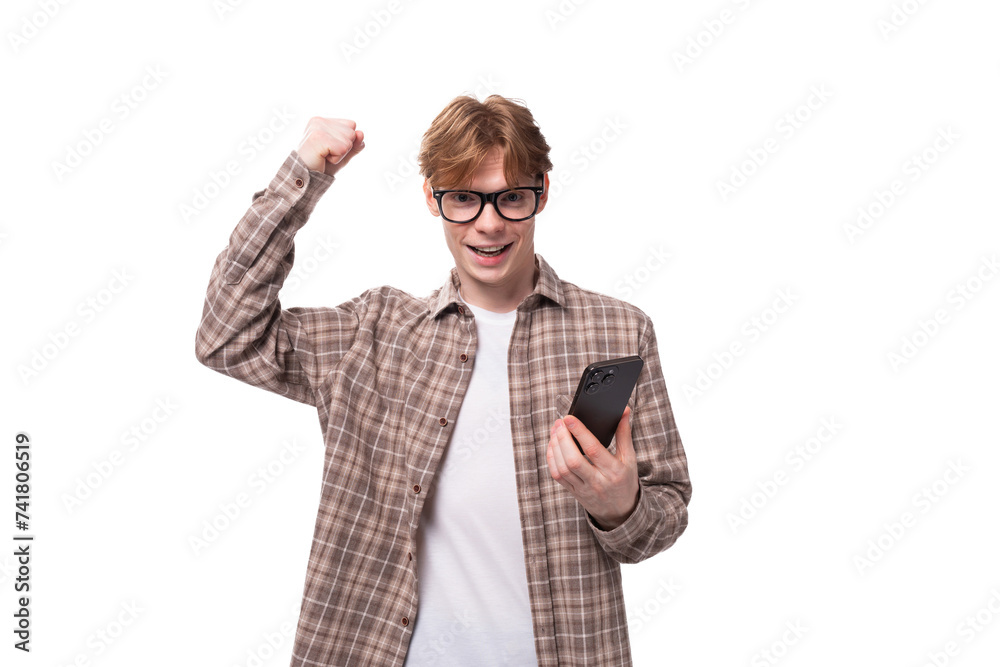 portrait of a young handsome caucasian red-haired guy in a shirt with a phone in his hand portrait of a young handsome caucasian red-haired guy in a shirt with a phone in his hand
