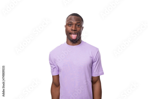 young cheerful african man with a short haircut dressed in a lilac t-shirt makes a grimace