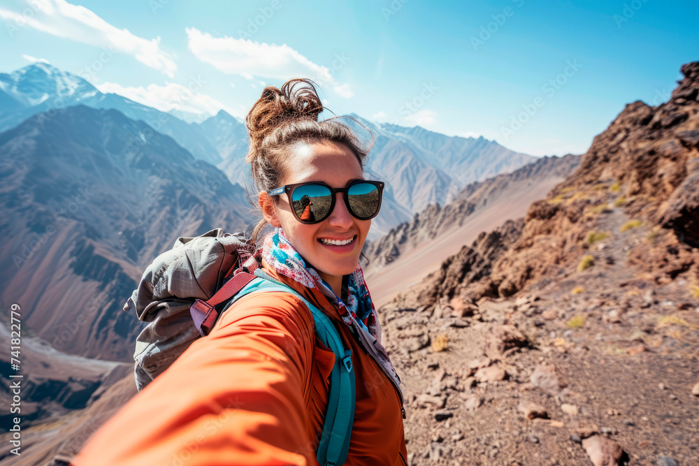 Mountain Memories: Joyful Traveler with Backpack Snaps Selfie against Toubkal Peak, Reveling in the Spectacular Scenery of Morocco's High Atlas Range.