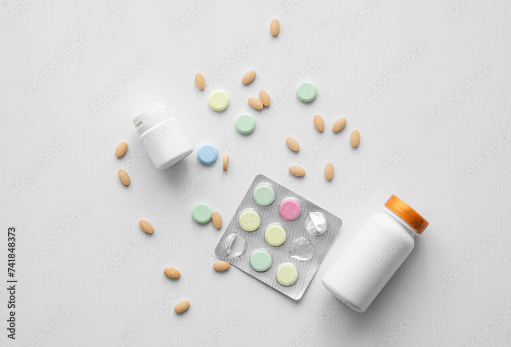 Assorted pills, vitamins and nutritional supplements in different colors with white bottles on a white background. Health medicine concept. Top view and copy space. Assorted pills, vitamins and nutritional supplements in different colors with white bottles on a white background. Health medicine concept. Top view and copy space.