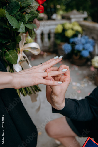 Close-up photo of a man putting on a wedding ring to a girl after the proposal