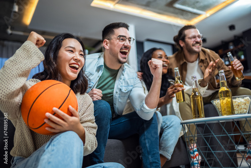 Multiracial group of friends watching basketball game, drinking beer and cheering. © Mediteraneo