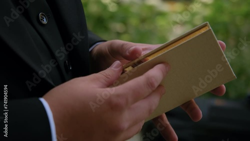 Unrecognizable groom opens vow book to read his vows to bride at wedding ceremony. Closeup shot male hands holding book 
