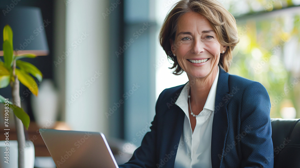 Happy mature middle aged professional businesswoman, working on a laptop in an office. Happy mature middle aged professional businesswoman, working on a laptop in an office.