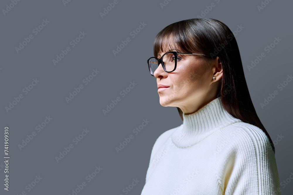 Profile portrait of mature serious woman, gray background, copy space