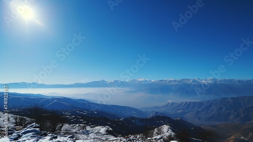 Breathtaking snowy mountain range under a clear blue sky, with the sun's rays accentuating the majestic peaks. Discover peaceful solitude and awe-inspiring beauty in this pristine winter won