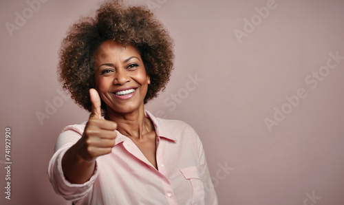 Beautiful happy afro american lady with thumb up, isolated on pink background photo