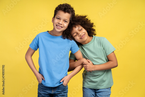Smiling African American children cute brother and sister wearing stylish colorful clothes, hugging photo