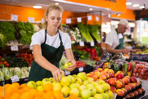 Fotografie Fifteen-year-old girl who works part-time in a store as a trainee saleswoman put