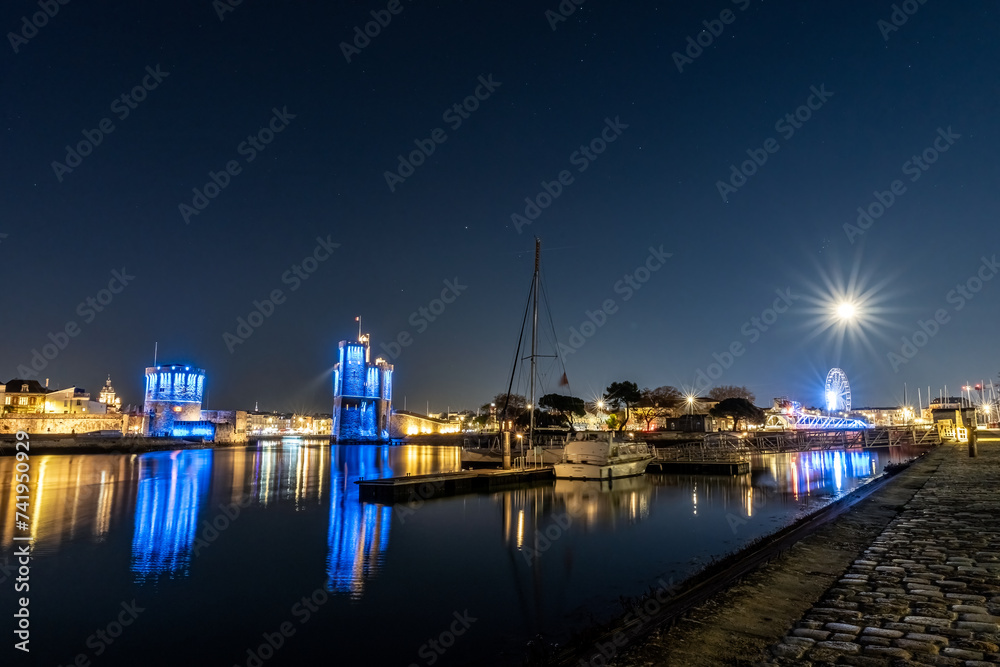 Panoramic view of the old harbor of La Rochelle at blue hour with its famous old towers.