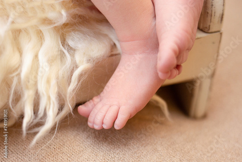 baby's leg lying on a crib close-up on a beige background, space for text, beige background. happiness concept