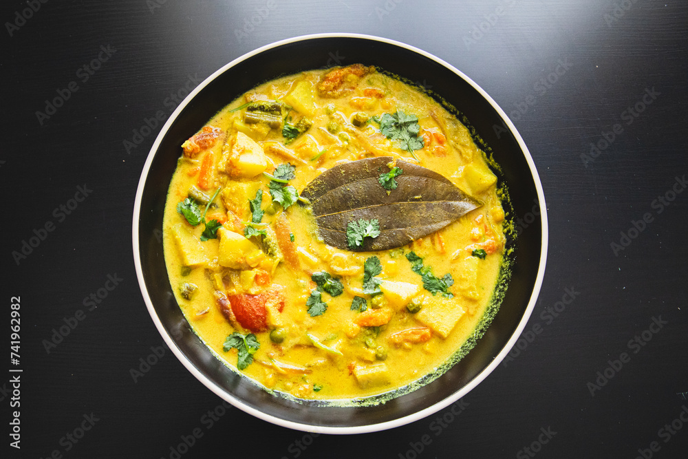 Potato curry in black bowl on dark slate background. Potato curry in black bowl on dark slate background.