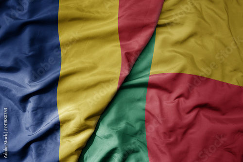 big waving national colorful flag of benin and national flag of romania .