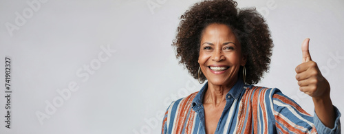 Beautiful happy African American lady with thumb up; isolated on light gray background and space for the text. photo