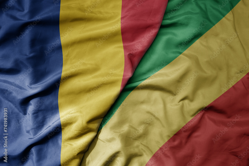 big waving national colorful flag of republic of the congo and national flag of romania .