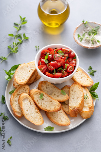 Making tomato basil crostini or bruschetta with toasted baguette