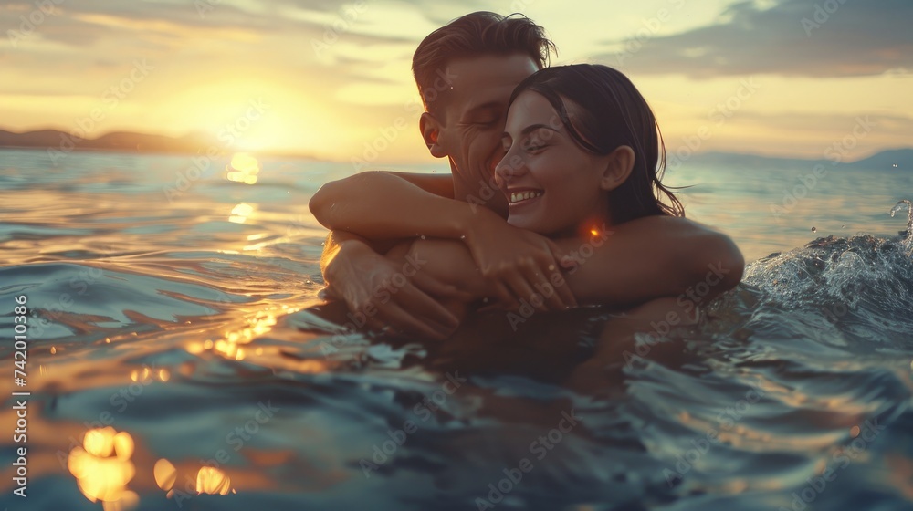 Happy young fit couple in the sea or ocean hug each other with love at summer sunset. Romantic mood, tenderness, relationship, vacation concept.