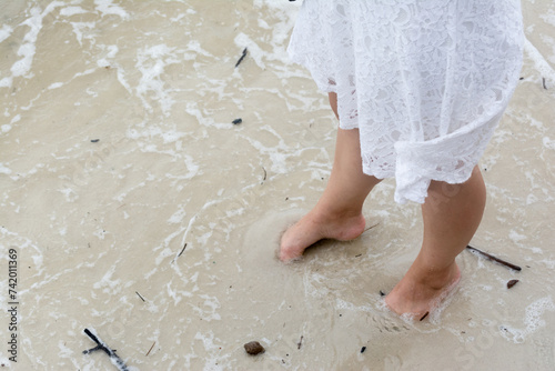 Half body of an unidentified person wet their feet in the beach sand. photo