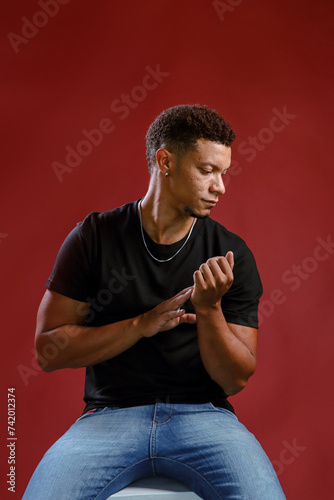 Portrait young african man looking down with red background