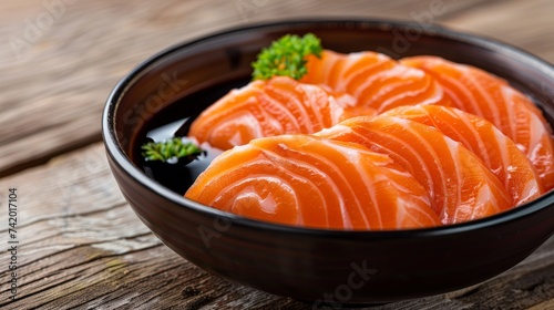 Salmon sashimi sushi put in bowl with sauce on wood background.