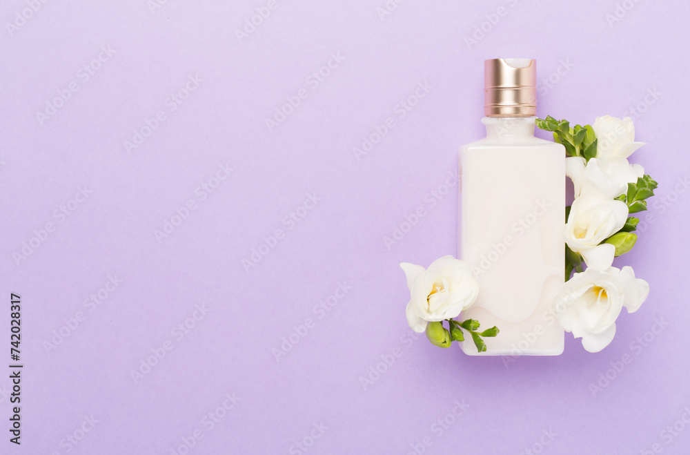 Cosmetic bottles with freesia flowers on color background, top view Cosmetic bottles with freesia flowers on color background, top view