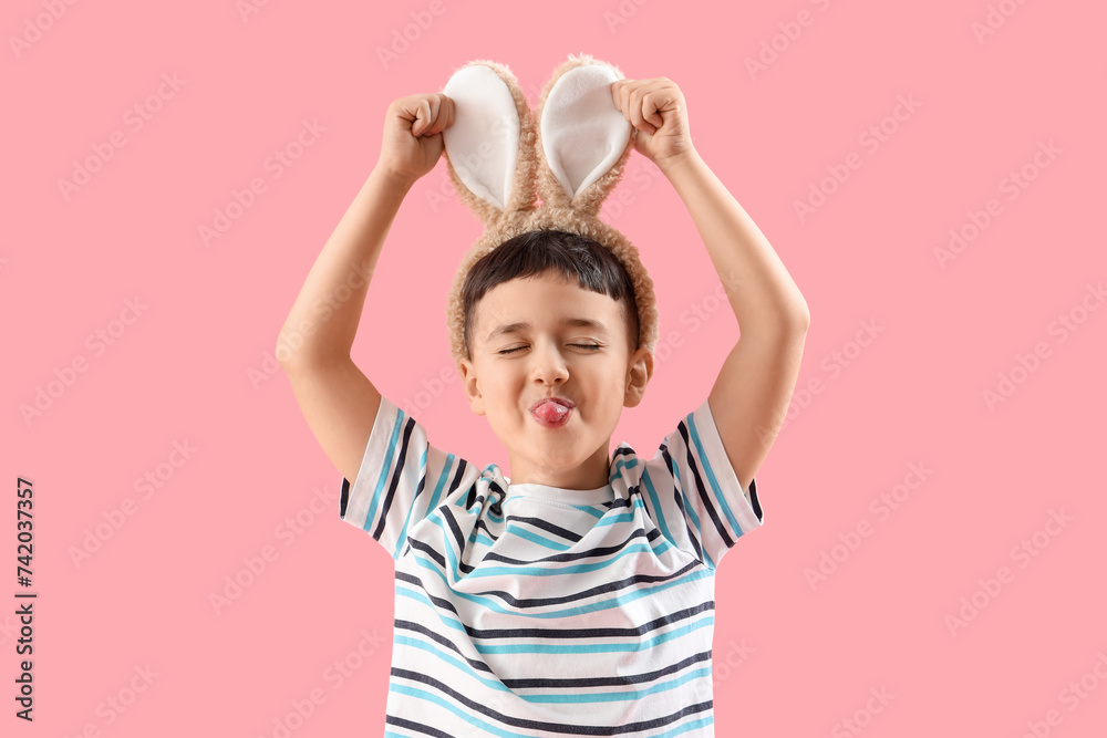Funny little boy wearing bunny ears on pink background. Easter celebration Funny little boy wearing bunny ears on pink background. Easter celebration