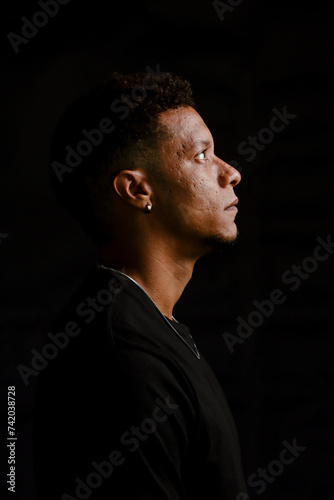 Obraz na płótnie Low key portrait of young African man in serious profile looking up w salonie