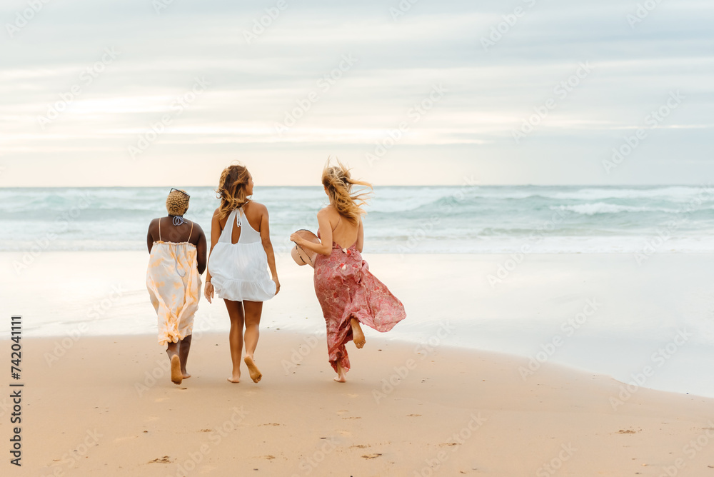 multiracial group of three friends enjoying a walk on the beach. 