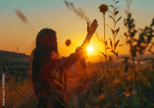 woman holds hand up to the sun at sunset, in the style of realistic depiction of light
