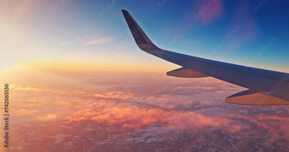 Airplane fly over snowy mountain hills during scenic sunrise with color sky cloudscape  , view from plane window of wing turbine and skyline 4k video