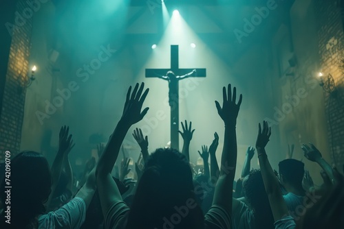 Christian worshipers raising hands up in the air in front of the cross