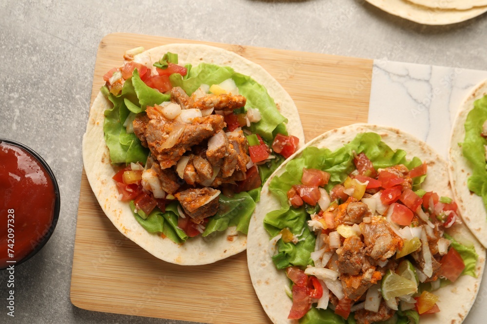 Delicious tacos with vegetables and meat on grey textured table, flat lay Delicious tacos with vegetables and meat on grey textured table, flat lay
