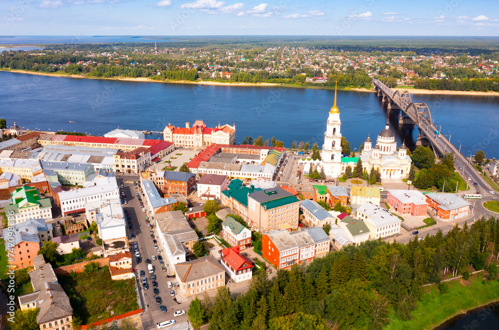 Aerial panoramic view of Rybinsk cityscape overlooking automobile bridge across Volga river and medieval Spaso-Preobrazhensky Cathedral with belfry in historical part of city, Yaroslavl region..