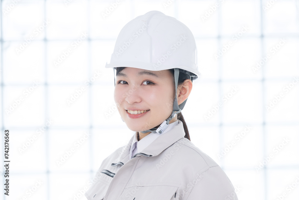 作業着を着たカメラ目線のヘルメットを被る女性のクローズアップ