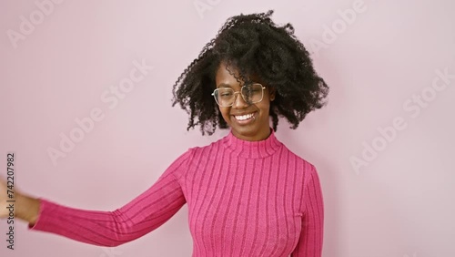 Joyful african american woman standing, saying a happy hello, waving in friendly welcome gesture while wearing glasses, smiling beautifully photo