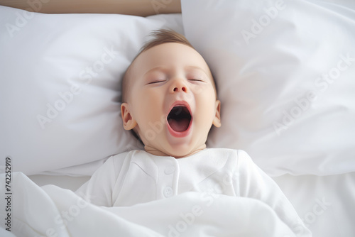 Cute baby sleeping and yawning on white sheets