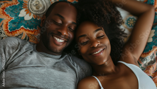 A couple shares a warm, intimate moment, lying closely together with content smiles in a cozy, patterned environment photo