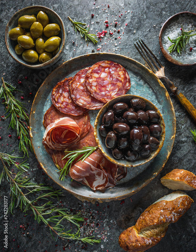 Geschmacksintensive Oliven mit eingelegten Peperoni und würziger Chorizo auf dunkler Granitplatte Darkfood Draufsicht Topview