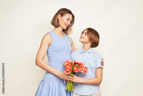 The boy gives his mother flowers and makes a surprise. Mother's day, congratulations on international women's day, flowers in hands
