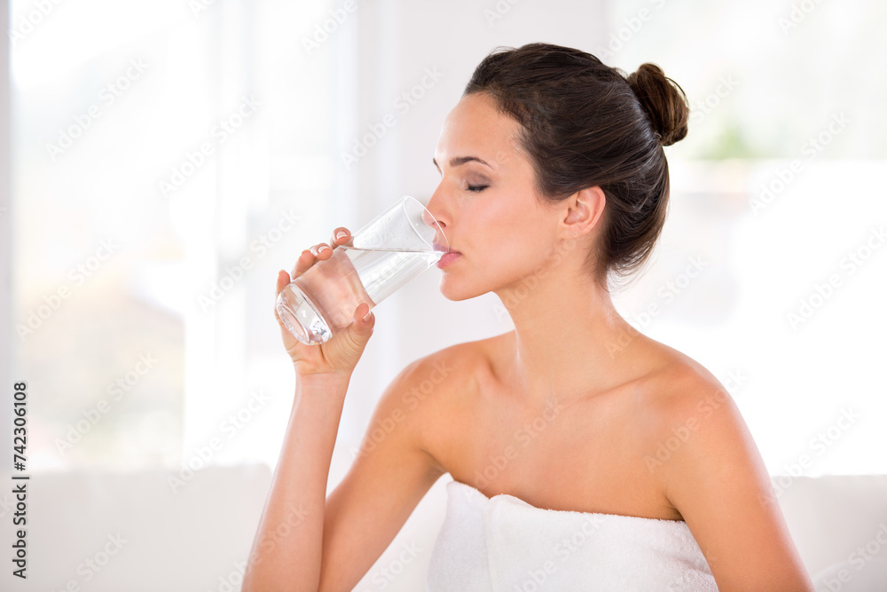 Home, woman and skincare with drinking water in towel for routine, treatment and body care in living room. Female person, hydration and smooth with cosmetic for natural glow, soft and confidence.