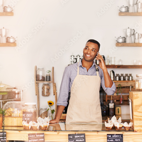 Planning, smile and phone call with black man in coffee shop for communication, networking or service. Cafe, restaurant and thinking with happy young small business owner or vendor working in bakery