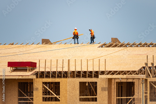 Roofing on roof. Builder roofer install new roof. Construction worker roofing on a large roof apartment building development. Roofer carpenter working on roof structure construction site. photo